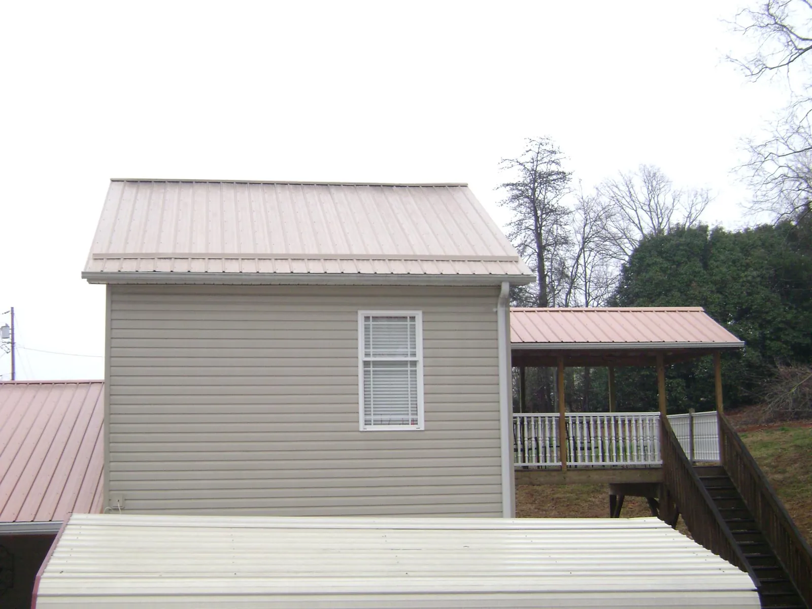 Tan metal roofs on a two story addition and attached porch, from a Roof Replacement job in Scranton
